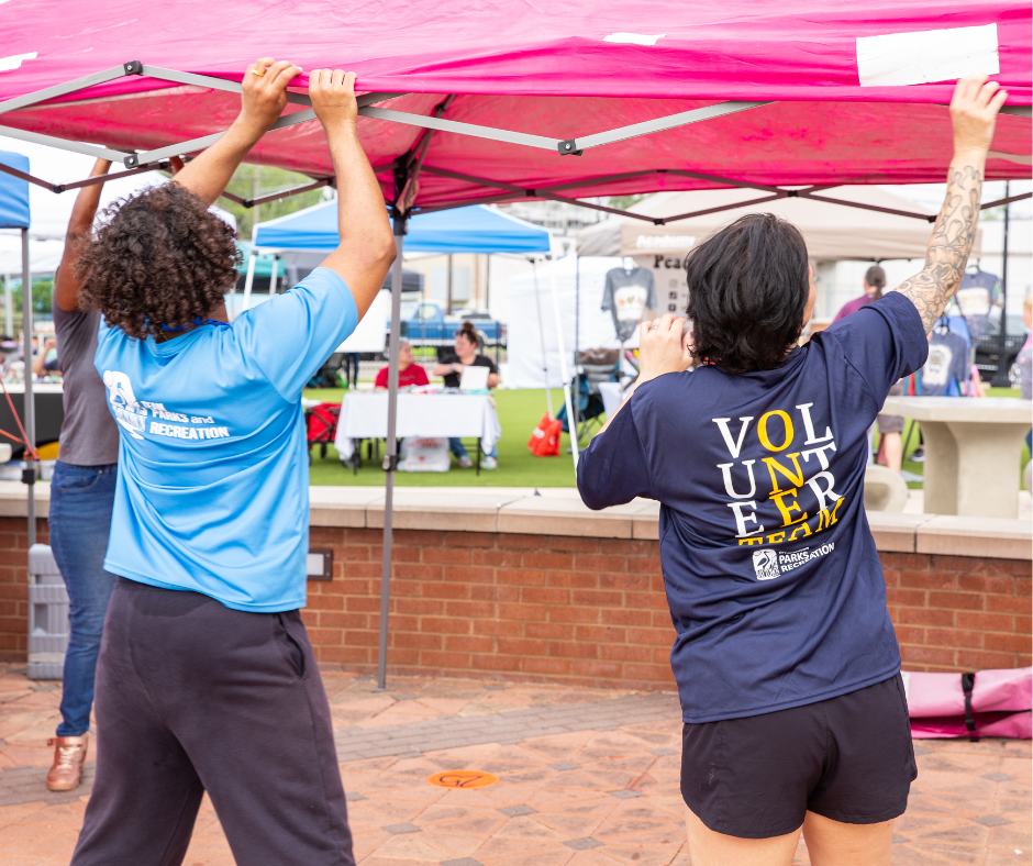 Two people setting up a pop up tent. 