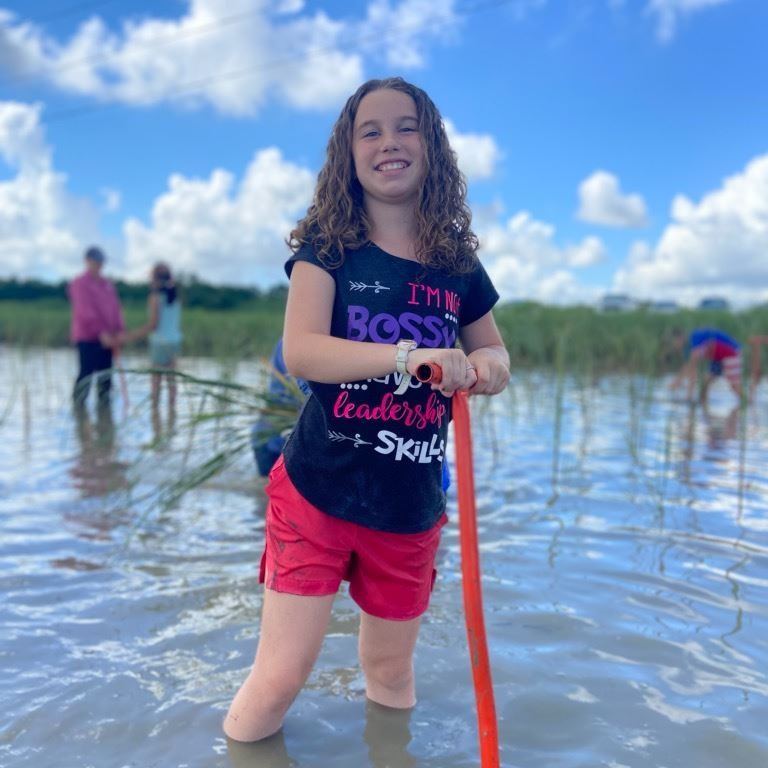 Girl planting marsh grass.