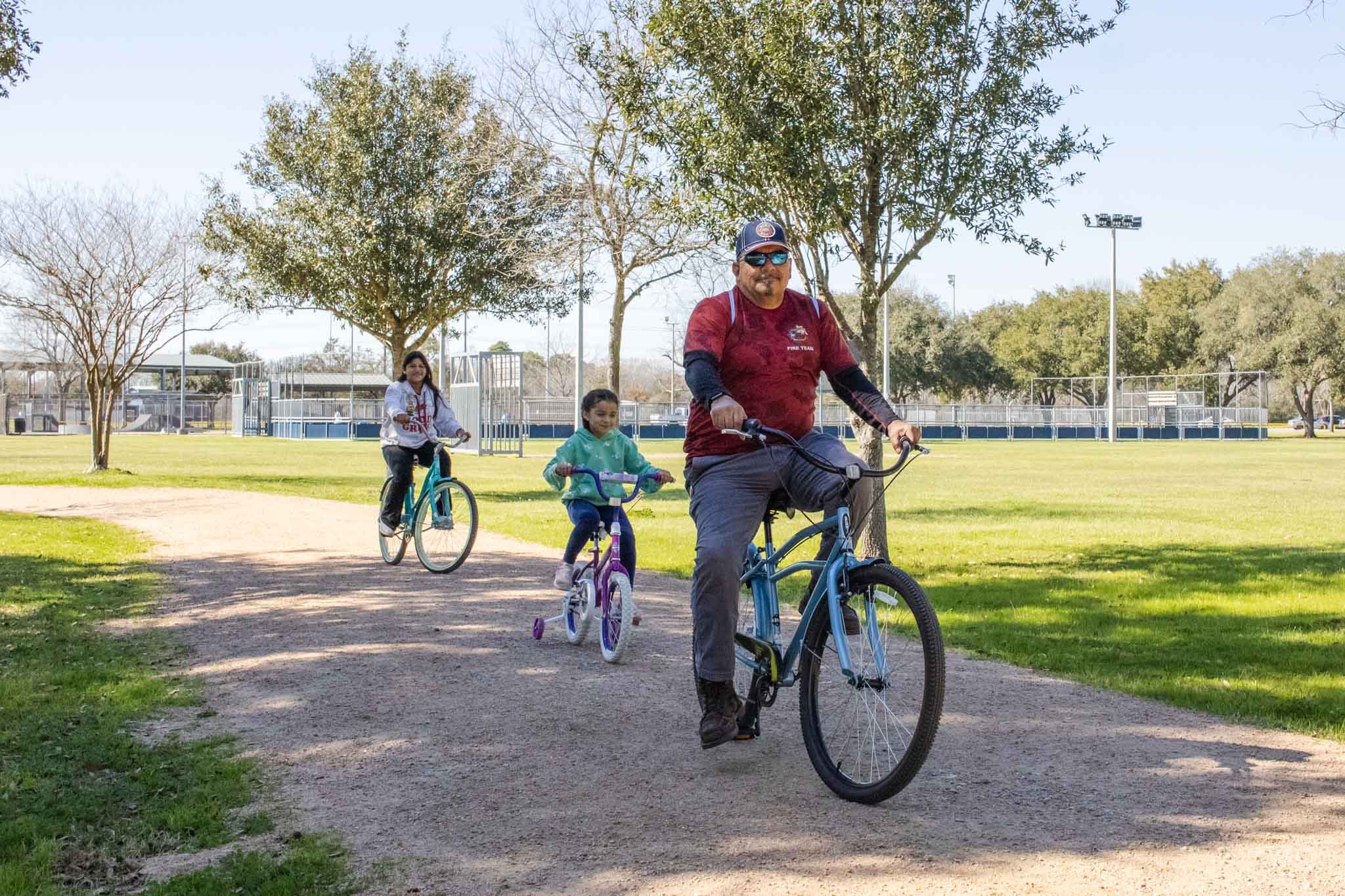 A family of three riding bikes on a trail at W.L. Jenkins Park